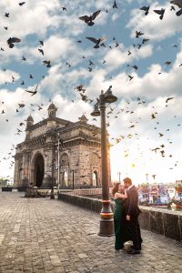 couple is standing beside of gateway of india